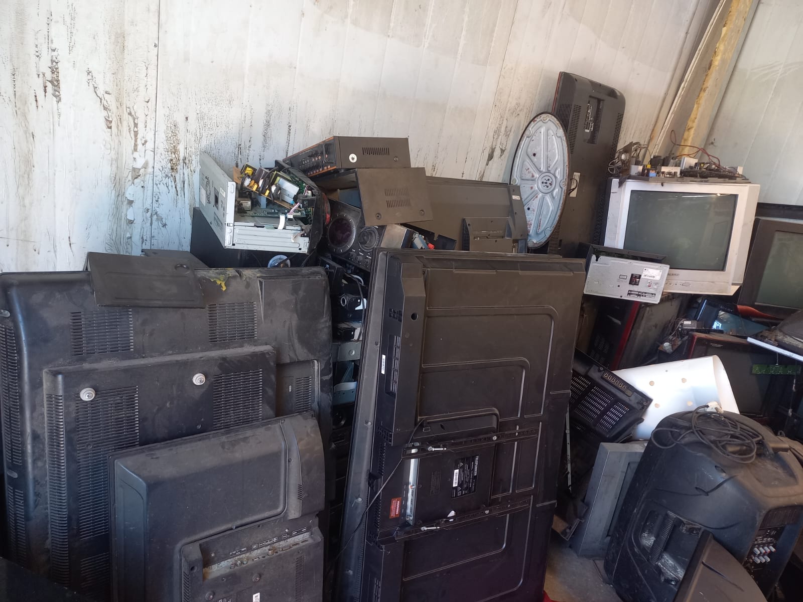 Stack of older televisions and AV equipment in storage